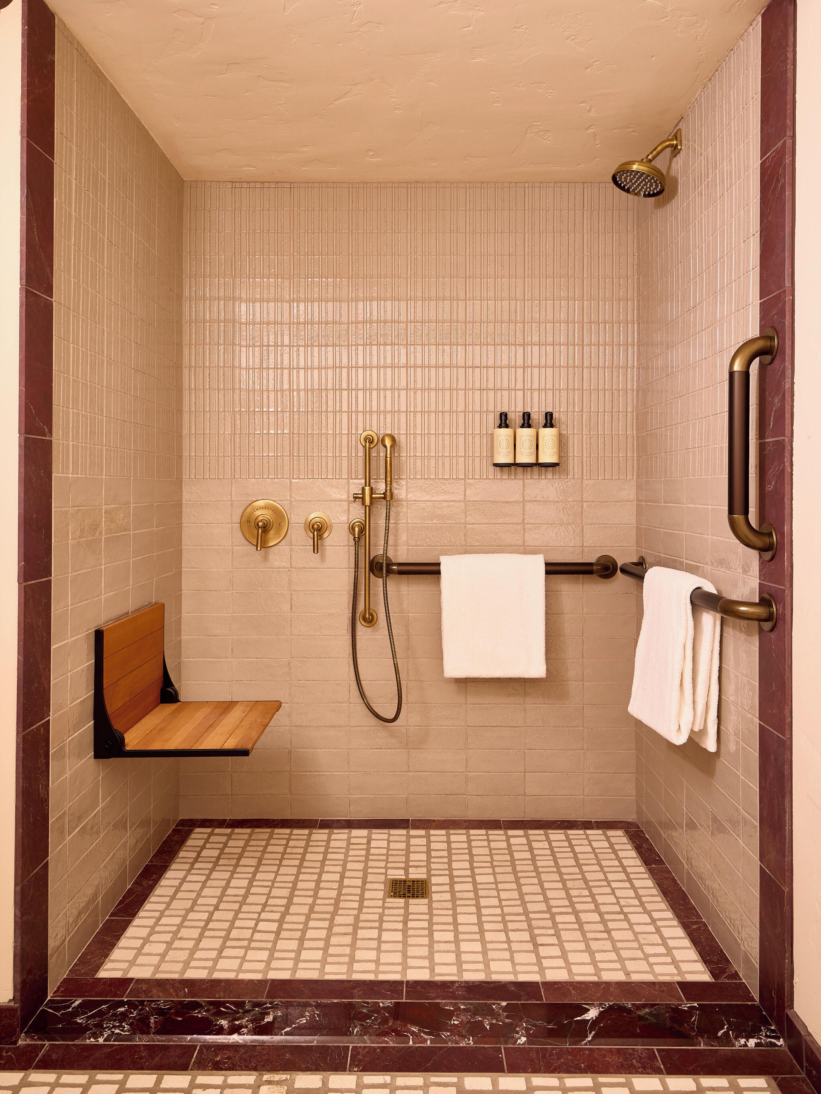 Ducha con cabezal de ducha de mano, un accesorio de ducha manual y un perchero con dos toallas.