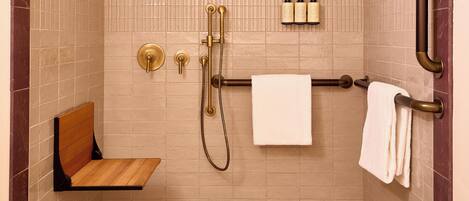 Ducha con cabezal de ducha de mano, un accesorio de ducha manual y un perchero con dos toallas.