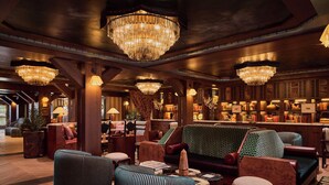 A lobby with multiple seating areas, chandeliers, and a bar area with various items. - Faraway Jackson Hole (Teton Village)