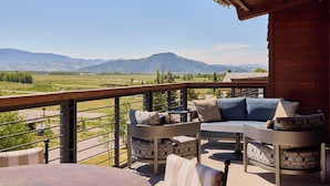 A balcony with outdoor furniture, a view of mountains, and a wooden structure. - Faraway Jackson Hole (Teton Village)