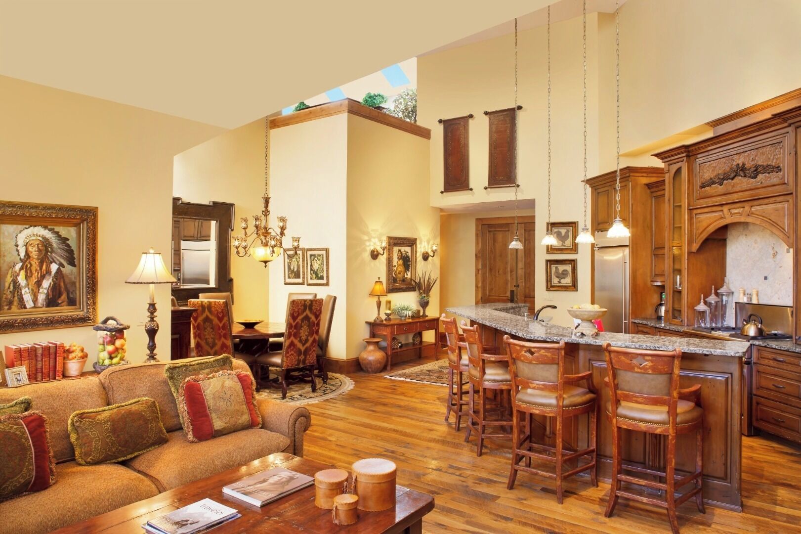 A spacious living room with a large sofa, a dining area, and a kitchen with wooden cabinets and a bar.