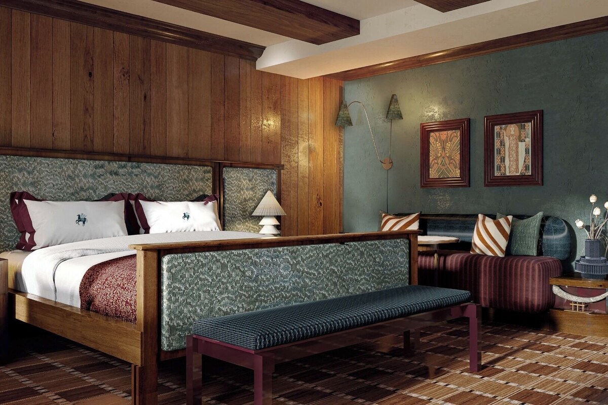 A bedroom with a large bed, a bench, a sofa, and a small table with a vase.