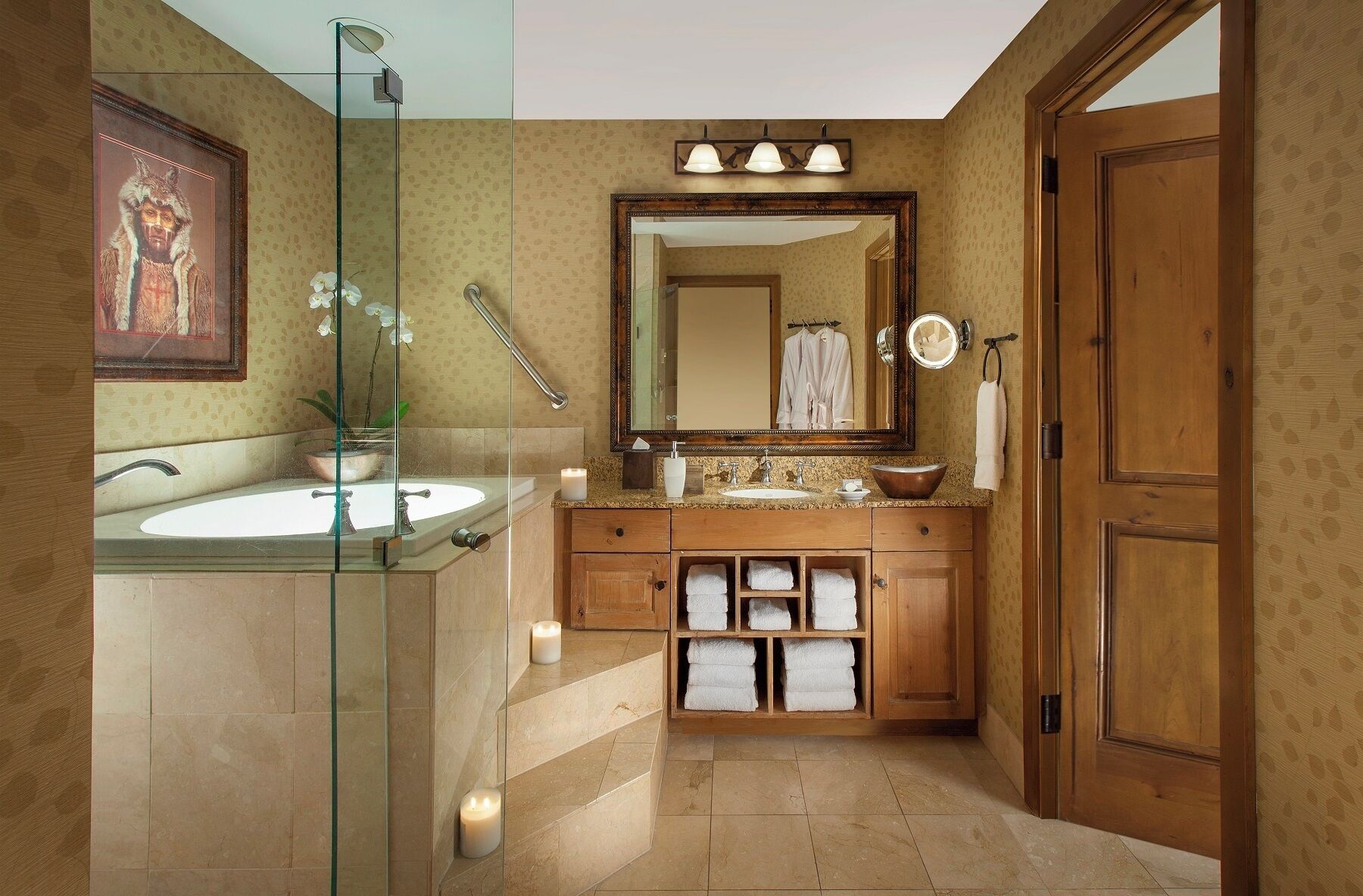 A bathroom with a glass shower enclosure, a large mirror, a sink with a vanity, and a wooden door.
