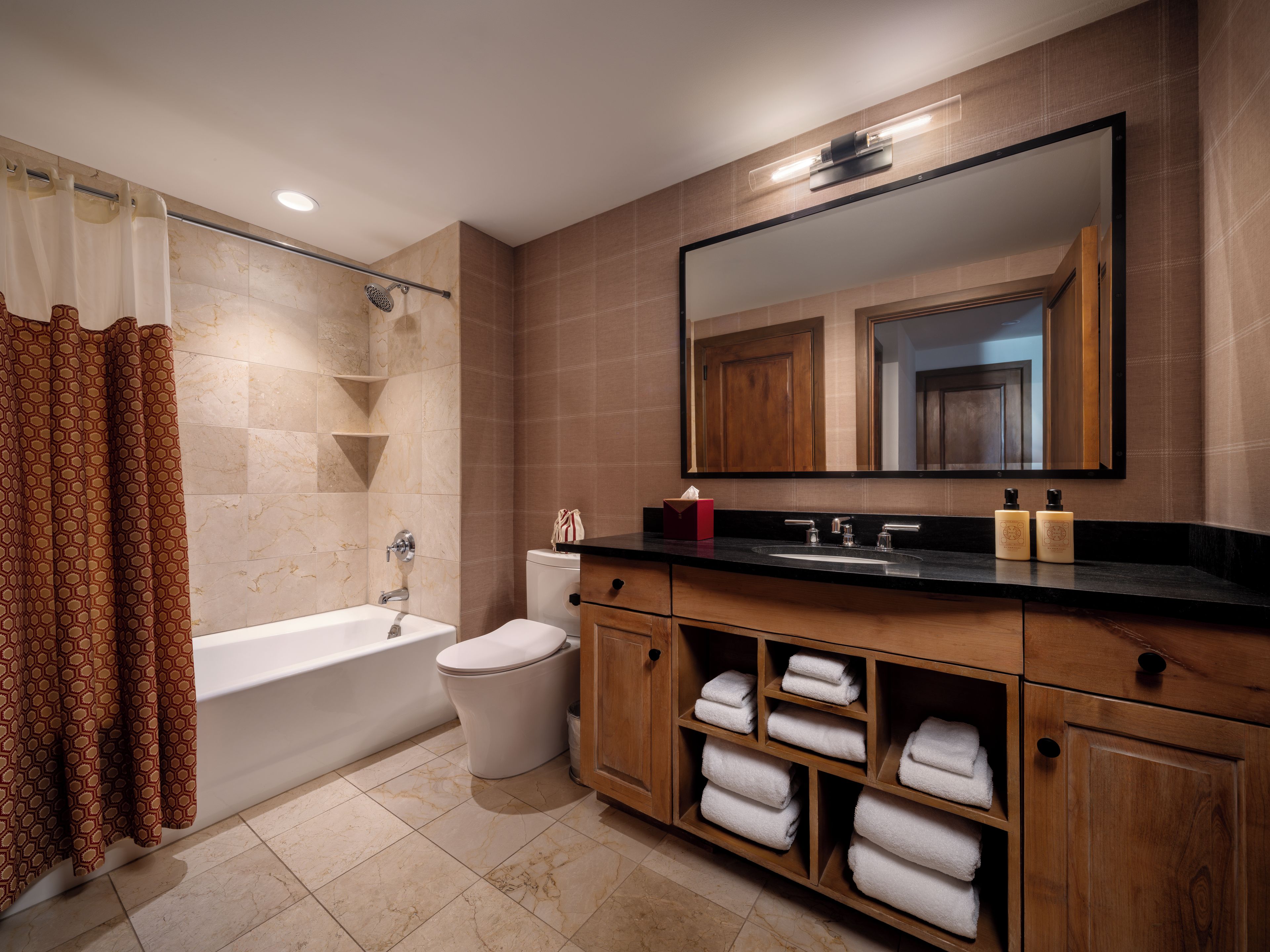 A modern bathroom with a bathtub, toilet, vanity, and a large mirror.