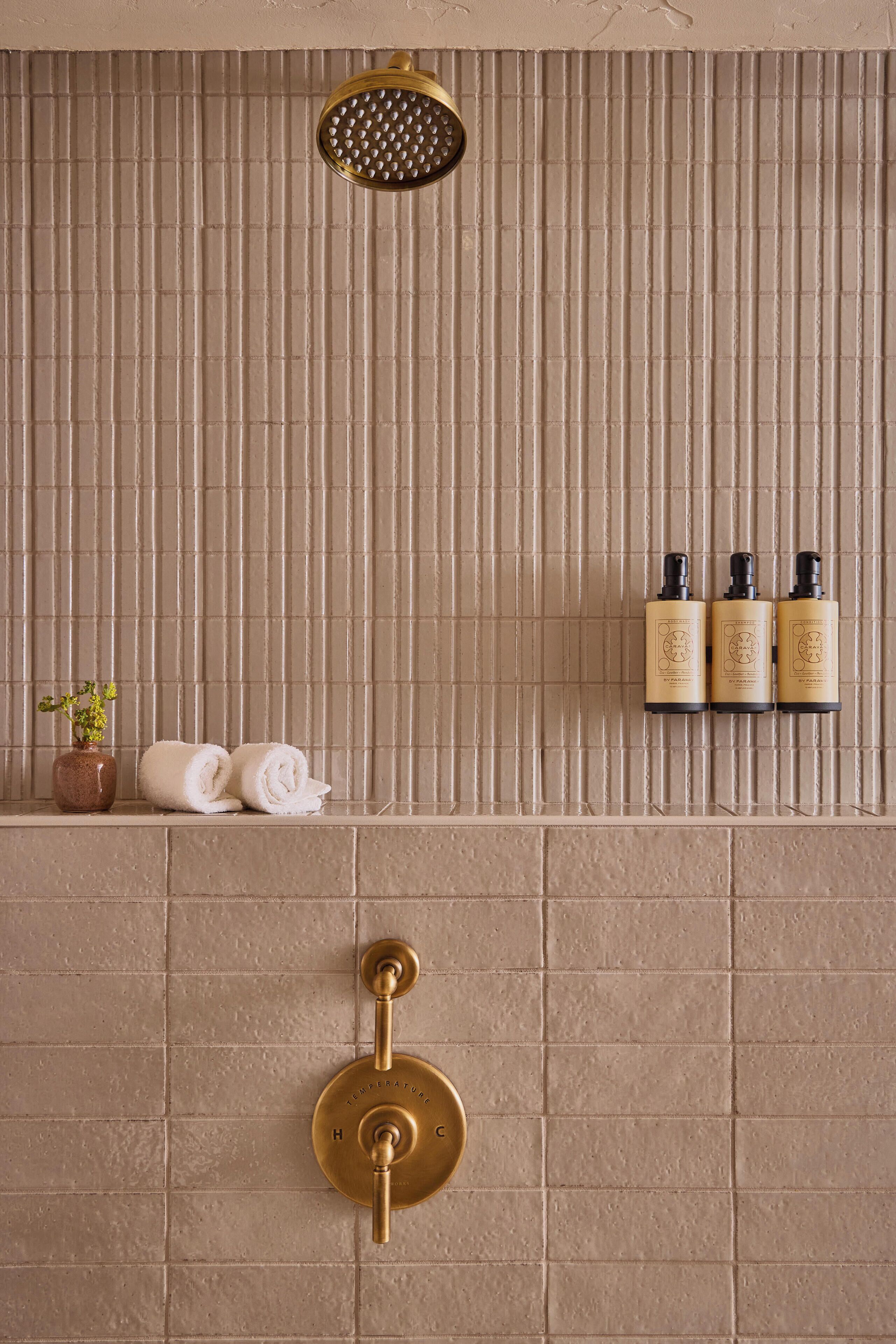 Un bagno con doccia, un portasciugamani e tre flaconi di shampoo.