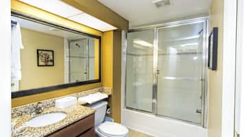 A bathroom with a double sink vanity, a toilet, and a glass-enclosed shower.
