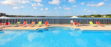 A swimming pool with a view of a body of water and distant buildings.