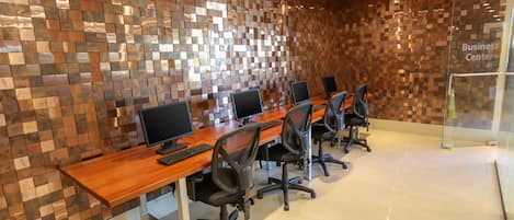 A conference room with a long wooden table, multiple computer monitors, and office chairs.