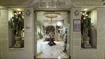 The entrance of Serenity Spa by Westgate, featuring a grand chandelier, a reception desk, and decorative statues.
