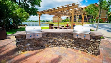 An outdoor grill area with stone walls and a wooden pergola.