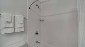 A bathroom with a toilet, a shower with a glass door, and a towel rack with multiple towels.
