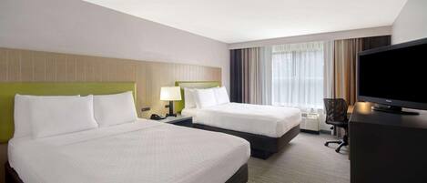 A hotel room with two beds, a television, a desk, and a chair.