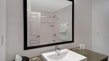 Un baño moderno con un espejo grande, lavamanos blanco y un perchero para toallas.