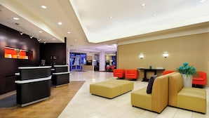 Un hall d’hôtel moderne comprenant un comptoir d’accueil, un espace détente et un bureau d’enregistrement.