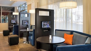 Un hall d’hôtel moderne doté d’un espace salon, d’un bar et d’un écran de télévision.