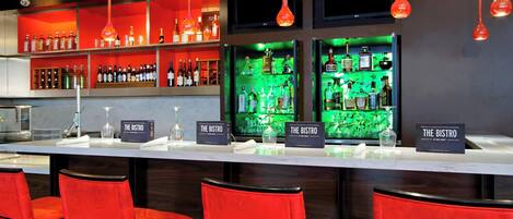 A bar area with red chairs, shelves of liquor bottles, and illuminated signs reading "The Bistro".