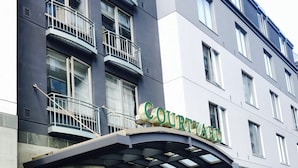 Un hôtel à plusieurs étages, avec une enseigne bien visible indiquant « COURTYARD » au-dessus de l’entrée.
