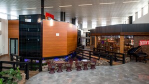 A modern interior with a reception desk, a piano, and outdoor seating area with chairs and tables. - Coast Nisku Inn & Conference Centre (Nisku)