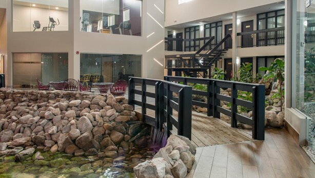 A spacious indoor area with a koi pond, wooden deck, and a staircase leading to upper floors. - Coast Nisku Inn & Conference Centre (Nisku)