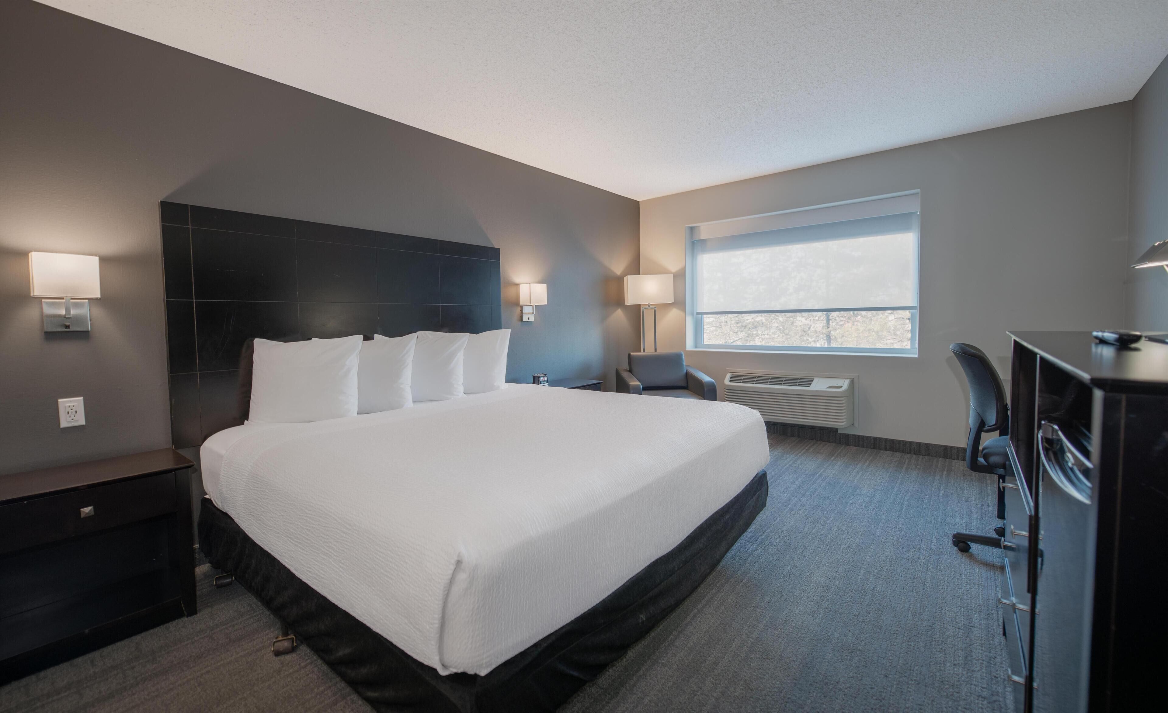 A hotel room with a large bed, bedside tables, a desk, and a chair.