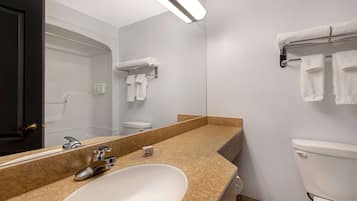 A modern bathroom with a large mirror, a white sink, a toilet, and a towel rack.