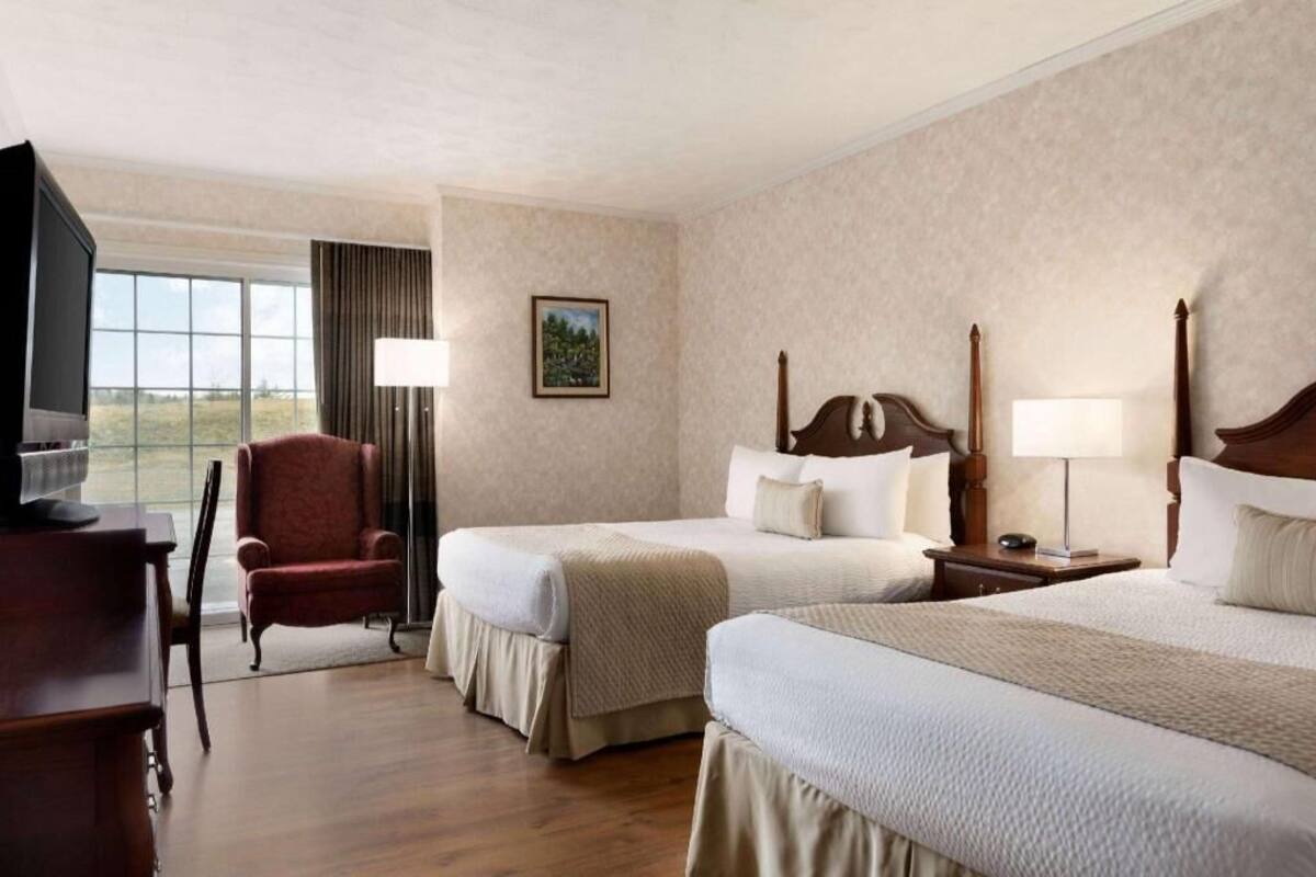 Habitación de hotel con dos camas, un televisor, una silla y ventana con vistas.