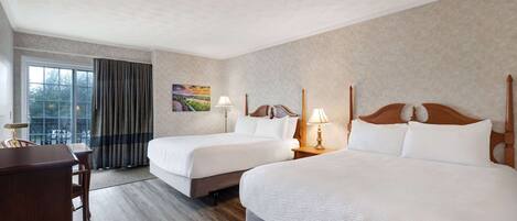 Habitación de hotel con dos camas, un escritorio y una ventana con cortinas.