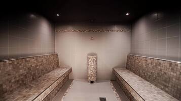 A modern bathroom with two benches, a tiled floor, and a central column.