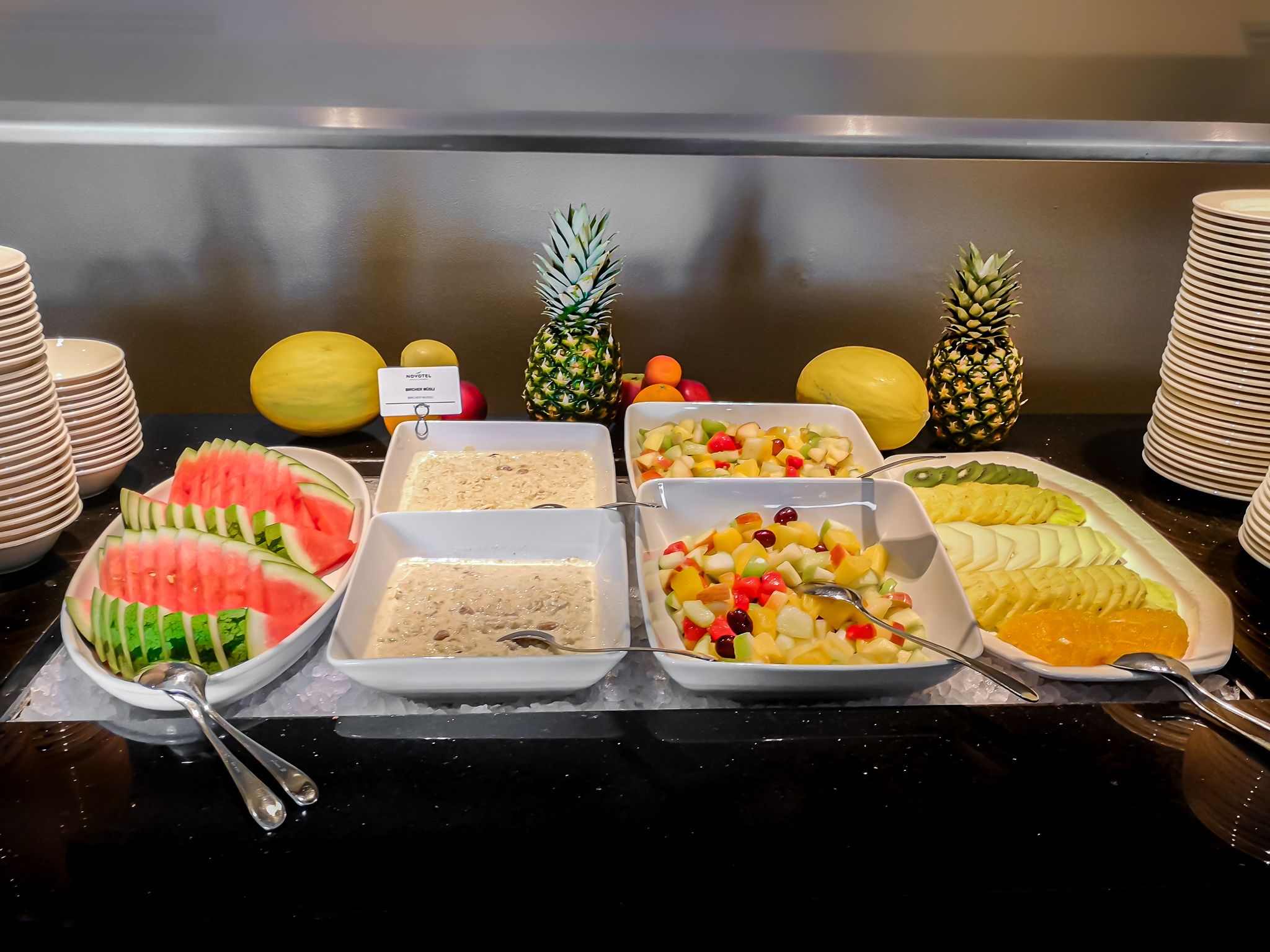 A buffet with various food options including watermelon, a fruit salad, and other dishes.