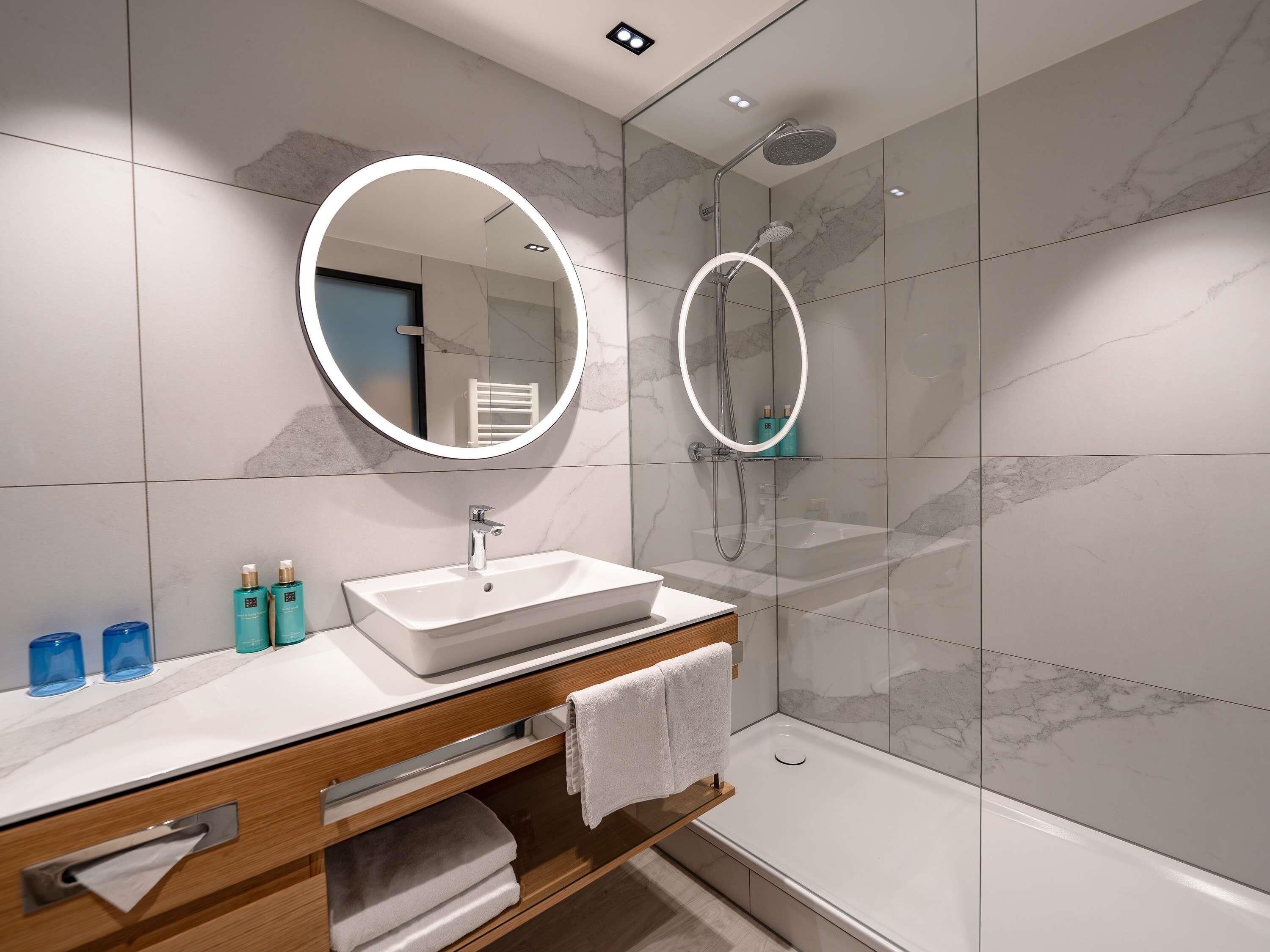 A modern bathroom with a white sink, mirror, and shower.