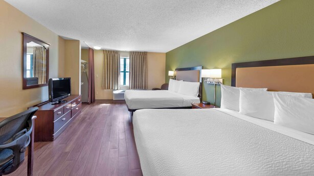 Una habitación de hotel con dos camas, televisión, escritorio y silla.