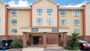 A multi-story hotel with a beige facade, a central lobby entrance, and a brick base.