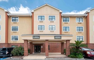 Um hotel de vários andares com fachada bege, entrada principal para o lobby e base de tijolos.