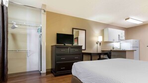 A hotel room with a bed, a desk, a television, a wardrobe, a shower, and a microwave.
