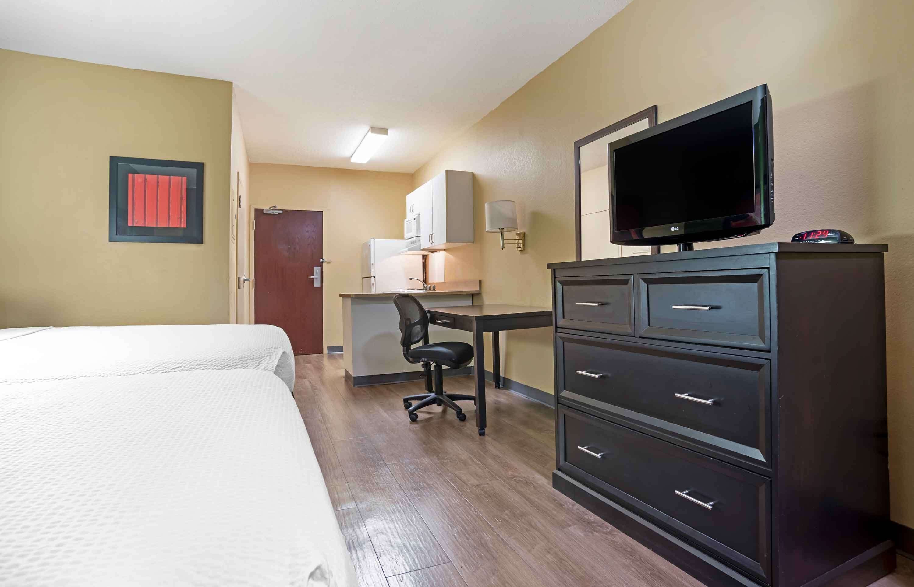 Een hotelkamer met een bed, een bureau met stoel, een televisie en een dressoir.