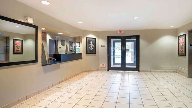 A spacious hallway with tiled flooring, framed artwork on the walls, and an exit sign.