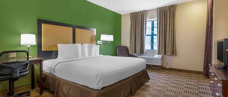 Habitación de hotel con una cama grande, dos lámparas de noche, un escritorio con silla, un televisor y una ventana con cortinas.