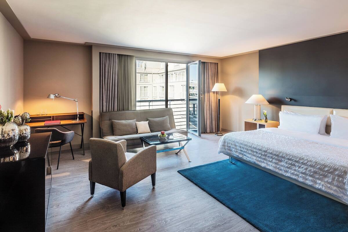 Hotellihuone, jossa on sänky, sohva, työpöytä ja sohvapöytä.