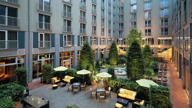 A courtyard with outdoor seating, greenery, and a fountain.
