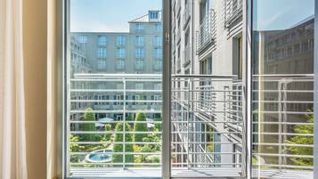 Una habitación de hotel moderna con un ventanal amplio que ofrece vistas a un edificio de varios pisos y una piscina.