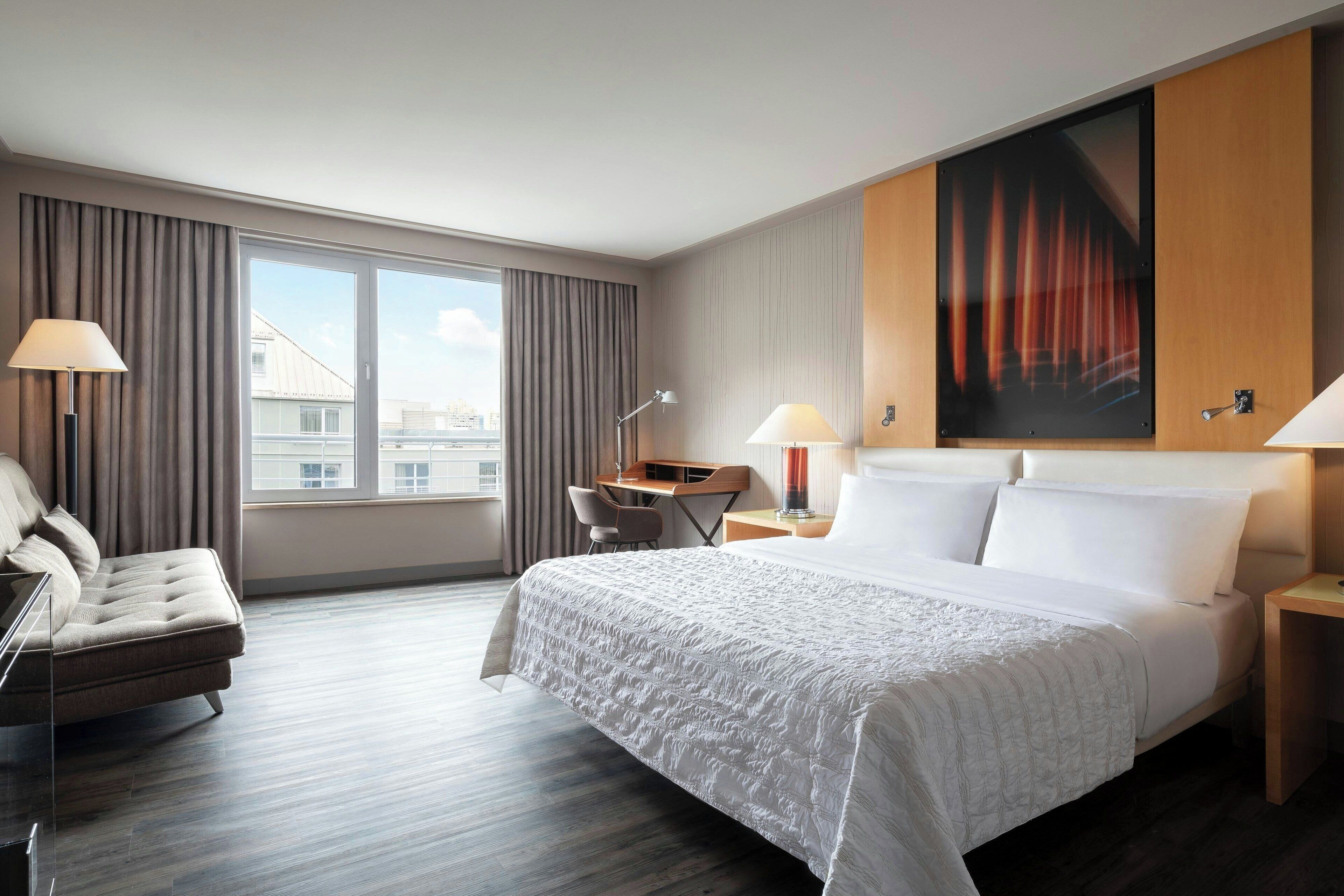A hotel room with a large bed, a desk, and a chair.
