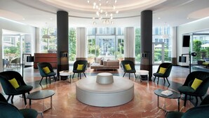 A spacious lobby with a central seating area, large windows, and a modern chandelier.