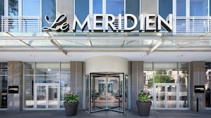 The exterior of a hotel with a revolving door entrance, large glass windows, and a prominent sign.