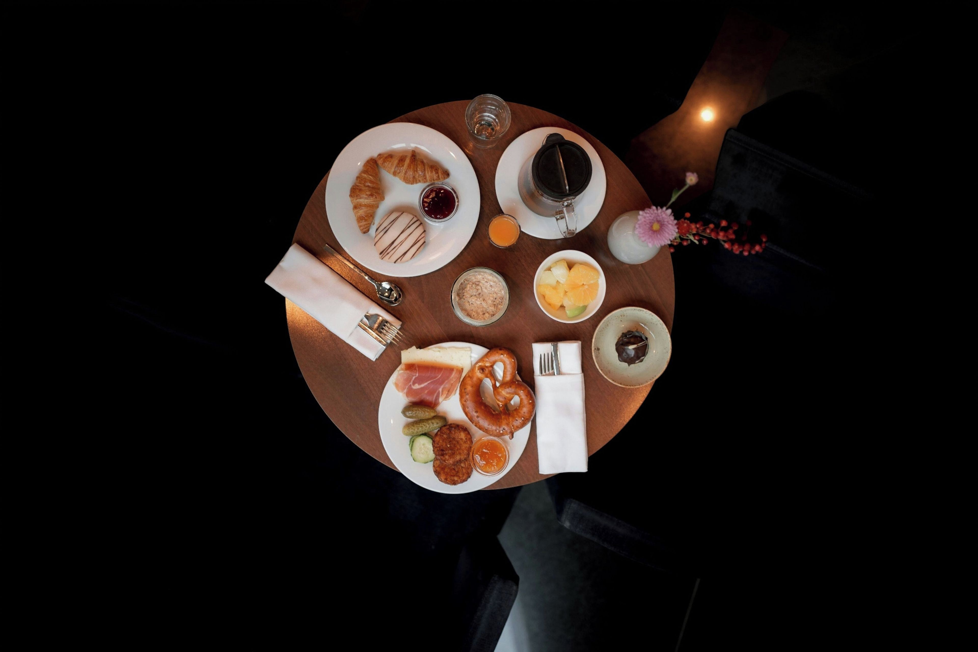A round table with various food items and a cup of coffee, set against a dark background.