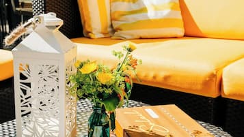 A dining area with a wicker table, a menu, a lantern, and a vase of flowers.