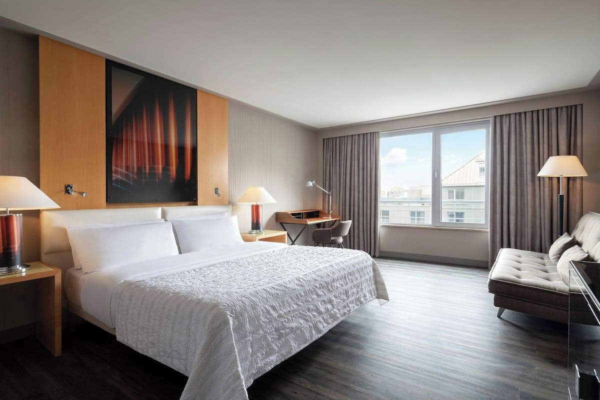 Moderni hotellihuone, jossa on suuri sänky, työpöytä, tuoli ja sohva.