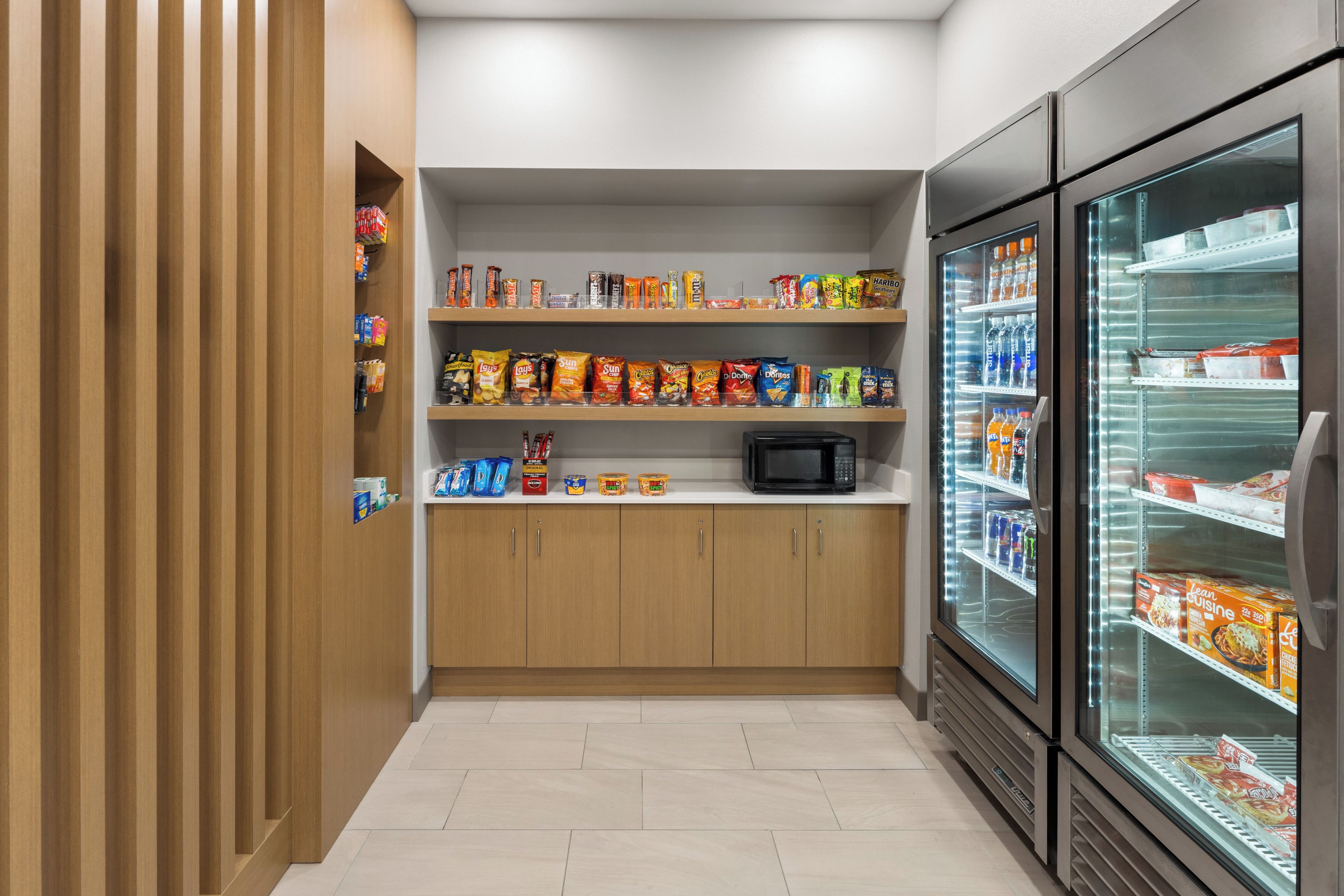 A snack and beverage kiosk with a microwave, shelves stocked with snacks, and a refrigerated display.
