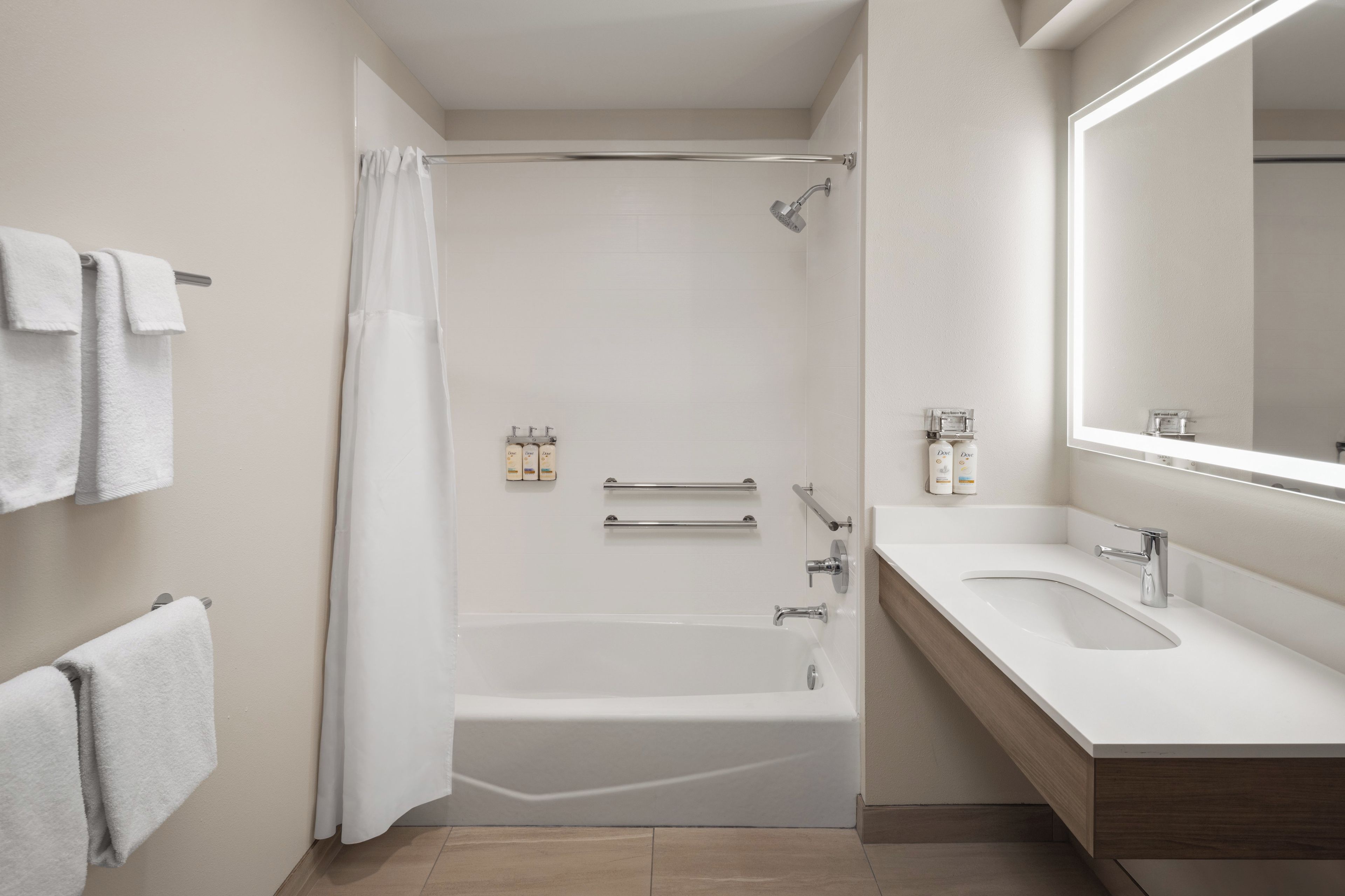 A modern bathroom with a bathtub, a shower, a sink, and a large mirror.