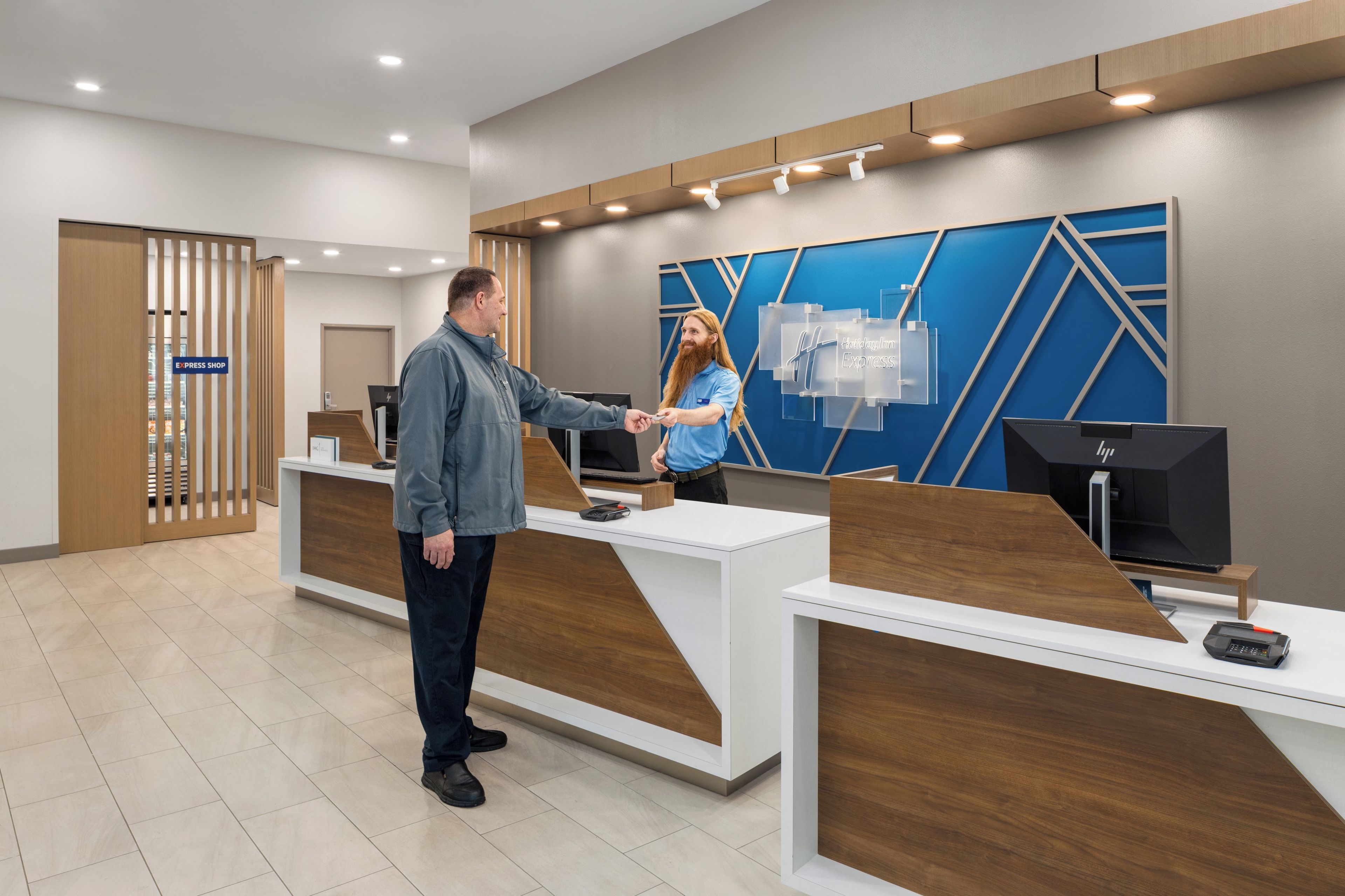 A reception area with a modern design, featuring a reception desk, a digital display, and a sign for the express shop.