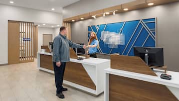 A reception area with a modern design, featuring a reception desk, a digital display, and a sign for the express shop.